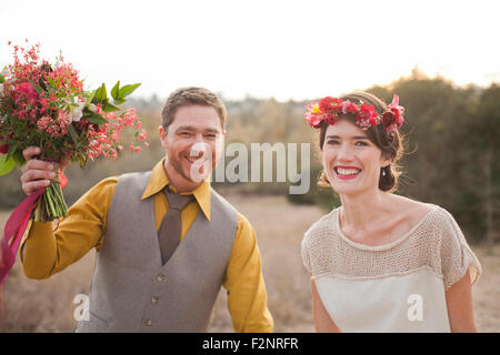 Bride and groom smiling in rural field Stock Photo