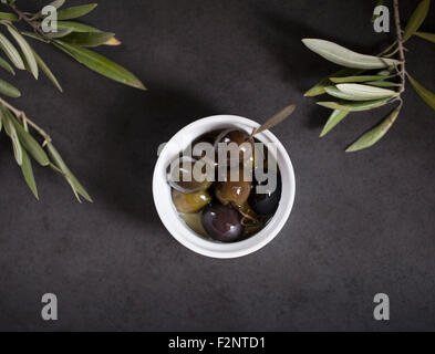 Black olives in dark background with olive tree leaves. Stock Photo