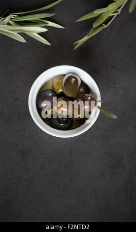 Black olives in dark background with olive tree leaves. Vertical image with copy space for you text. Stock Photo