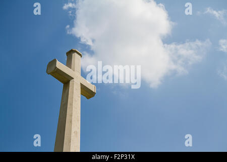 White Christian cross in front of a cloudy sky Stock Photo