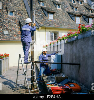 Telecom engineers installing a cellular telephone relay on ancient building, France Stock Photo