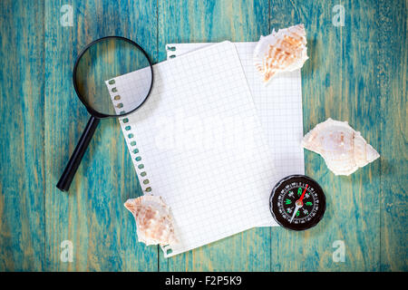 Paper sheets,seashells, compass and magnifying glass on wooden background Stock Photo