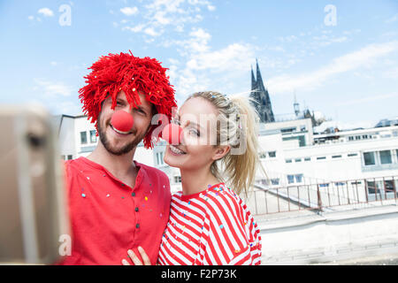 Germany, Cologne, young couple celebrating carnival dressed up as clowns Stock Photo