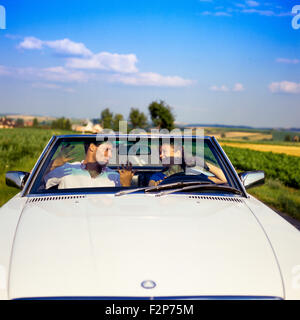 Couple having fun while driving a Mercedes convertible car on country road, Alsace, France Stock Photo