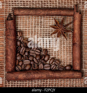 Decoration of cinnamon sticks, star anise and coffee beans on sacking Stock Photo