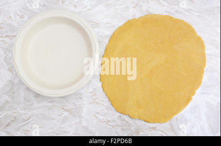 Fresh shortcrust pastry rolled out in a circle, ready to line ceramic pie dish Stock Photo