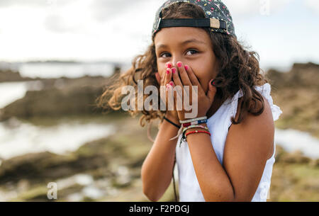 Spain, Gijon, portrait of little girl covering mouth with her hands Stock Photo