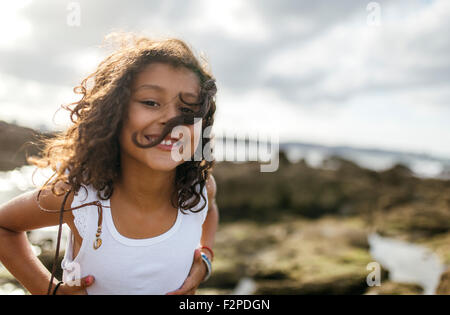 Spain, Gijon, portrait of smiling little girl at rocky coast Stock Photo