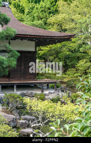 A traditional Japanese wooden building surrounded by trees in a formal garden setting Stock Photo