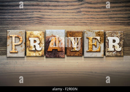 The word 'PRAYER' written in rusty metal letterpress type sitting on a wooden ledge background. Stock Photo