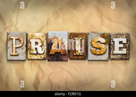 The word 'PRAISE' written in rusty metal letterpress type on a crumbled aged paper background. Stock Photo