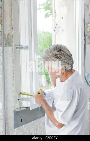 Mason measuring a window Stock Photo