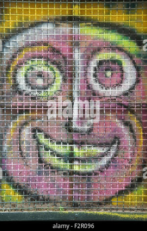 Ugly pink face. Colourful graffiti spray painted on a window shutter. Detail of urban street art by artist known as Loko. Montpellier, South of France. Stock Photo