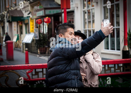 A couple taking selfie with a mobile phone, Chinatown, London, UK Stock Photo