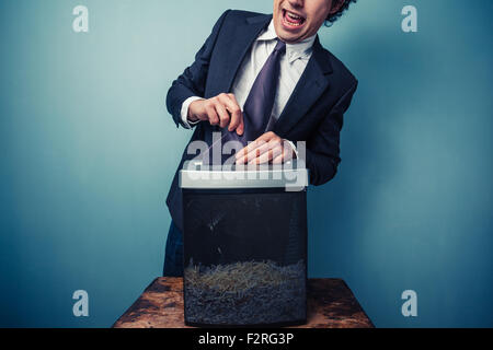 Clumsy businessman with his tie stuck in a paper shredder Stock Photo
