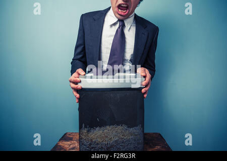 Businessman has got his tie stuck in a paper shredder Stock Photo