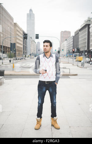 Young handsome indian contemporary business man walking through the city using smarpthone overlooking-  technology, network, business, finance concepts Stock Photo