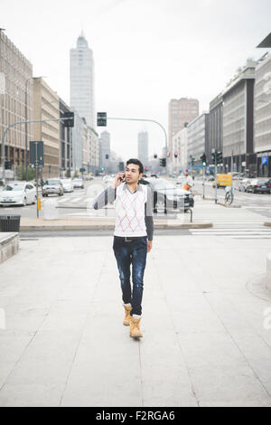 Young handsome indian contemporary business man walking through the city talking smarpthone -  technology, network, business, finance concepts Stock Photo