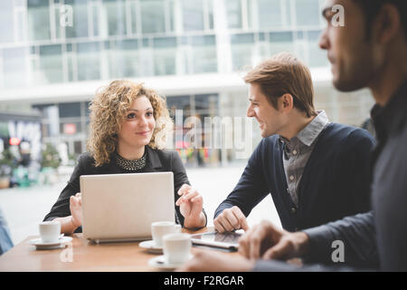 Multiracial contemporary business people working connected with technological devices like tablet and laptop, talking together, Stock Photo