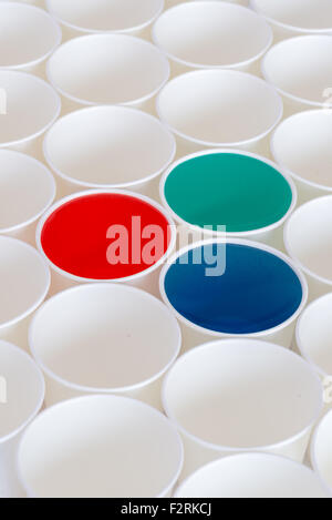 White paper cups on a white background. Some cups have colored liquid in them Stock Photo