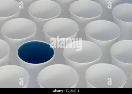 White paper cups on a white background. Some cups have colored liquid in them Stock Photo