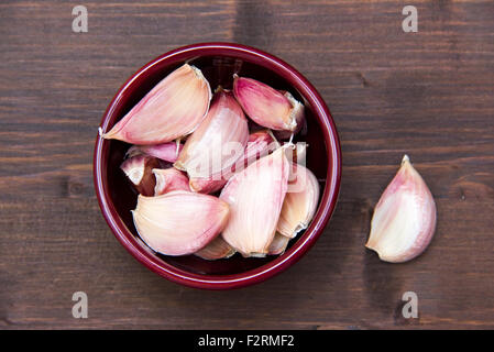 Cloves of garlic in bowl on wooden table seen from above Stock Photo