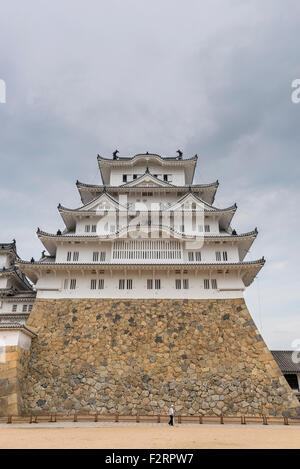 The main tower of Himeji Castle, one of Japan's UNESCO world heritage sites with a tourist in front for scale Stock Photo