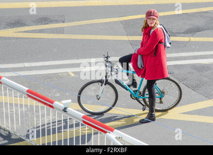 Girl on a bike waiting at the level crossing gates in England, UK. Stock Photo