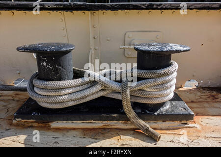 Secured mooring line / mooring rope / hawser laid in a figure-8 pattern around shipboard bitts on deck of ship Stock Photo