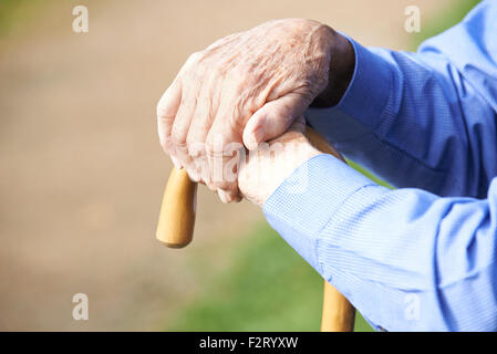 Close Up Of Senior Man's Hands Resting On Walking Stick Stock Photo