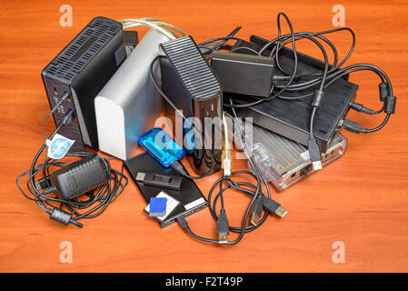 Many memory devices like hard disk drives or memory cards, in format USB or Firewire, with a lot of entangled cables Stock Photo