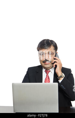 1 indian Business Man Laptop and Mobile Phone talking Multi Tasking Stock Photo