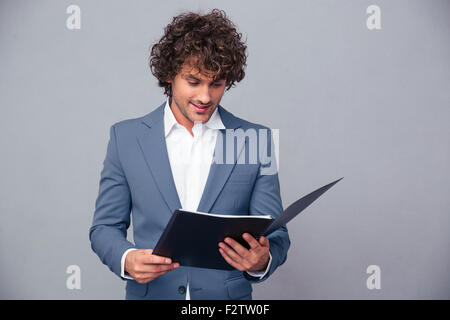 Portrait of a handsome businessman reading documents in folder over gray background Stock Photo
