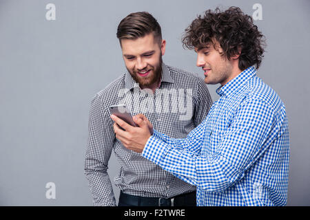 Portrait of a two happy men using smartphone over gray background Stock Photo