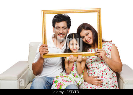 3 indian mother Pregnant and daughter with father home sofa sitting Picture Frame shwing Stock Photo