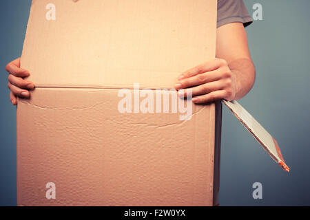 Young man is moving house and is holding a large cardboard box Stock Photo