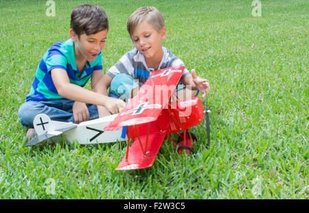 Two young boys playing with a model plane German Fokker DII from WWI in the yard at home MR-12 MR- 13 Model released Stock Photo