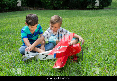 Two young boys playing with a model plane German Fokker DII from WWI in the yard at home MR-12 MR- 13 Model released Stock Photo