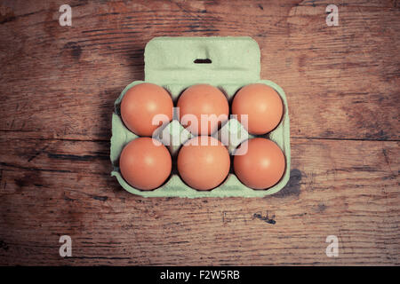 Six eggs in a cardboard tray on a wooden table Stock Photo