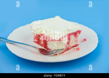 A piece of homemade soda-pop cake on a white dessert plate on a blue background.Made with strawberry soda,strawberry jello. USA. Stock Photo