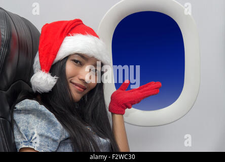 Woman with hat Santa Claus flies by plane Stock Photo