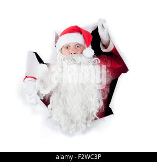 Santa Claus looking through hole in a white wall Stock Photo
