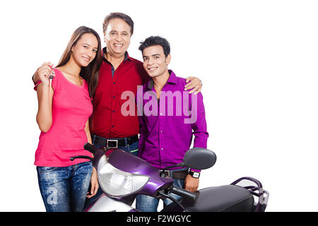 3 indian father and young son and daughter showing key Gift Scooty Stock Photo