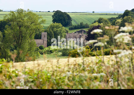 The Norman church of St Nicholas and Asthall Manor in the Cotswold village of Asthall, Oxfordshire UK Stock Photo