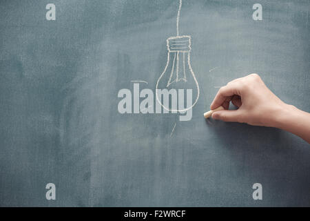 Human hand drawing electric lamp on a blackboard Stock Photo