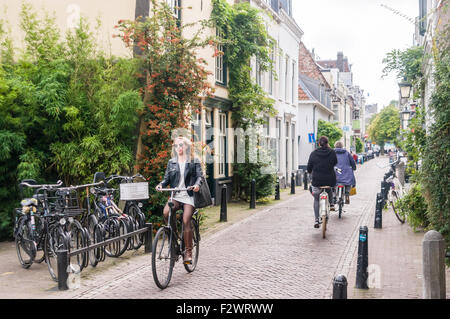 Cyclists riding down a pretty street in Utrecht, Holland, Netherlands Stock Photo