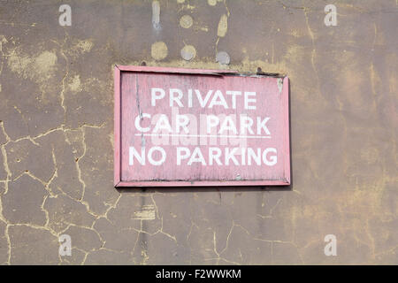 Faded and cracked wooden 'Private Car Park - No Parking' sign on wall in Bedford, Bedfordshire, England Stock Photo