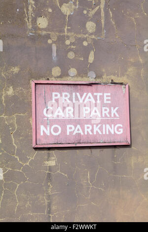 Faded and cracked wooden 'Private Car Park - No Parking' sign on wall in Bedford, Bedfordshire, England Stock Photo