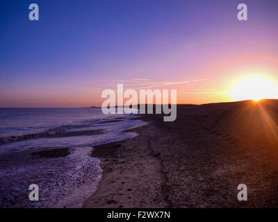 A view of a winter sunset on Dunwich beach, Suffolk, looking towards sizewell power station Stock Photo