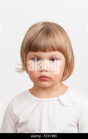 Cute serious Caucasian little girl, closeup studio portrait on light gray background Stock Photo